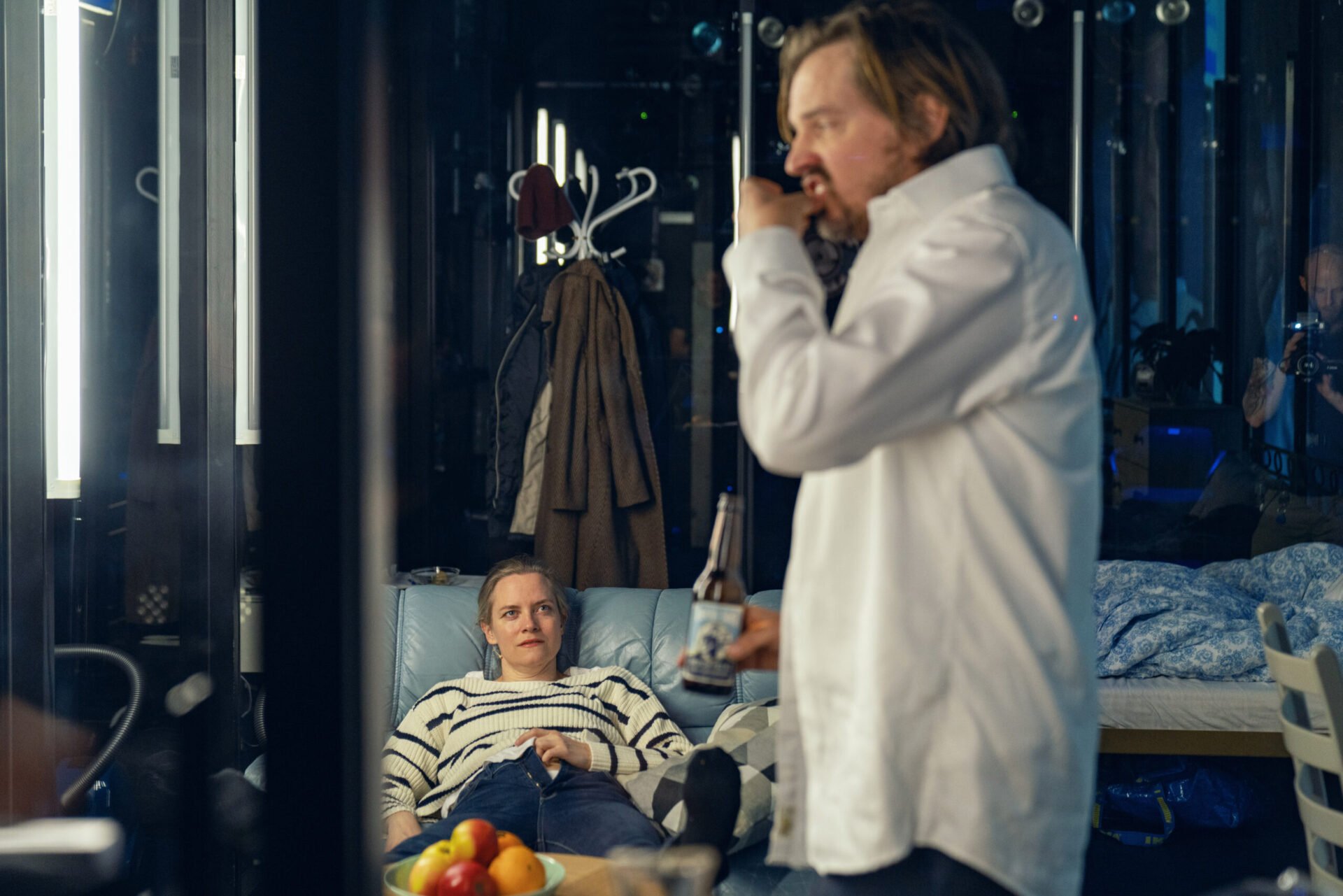 Kvinne ligger i en sofa og ser på en mann som spiser