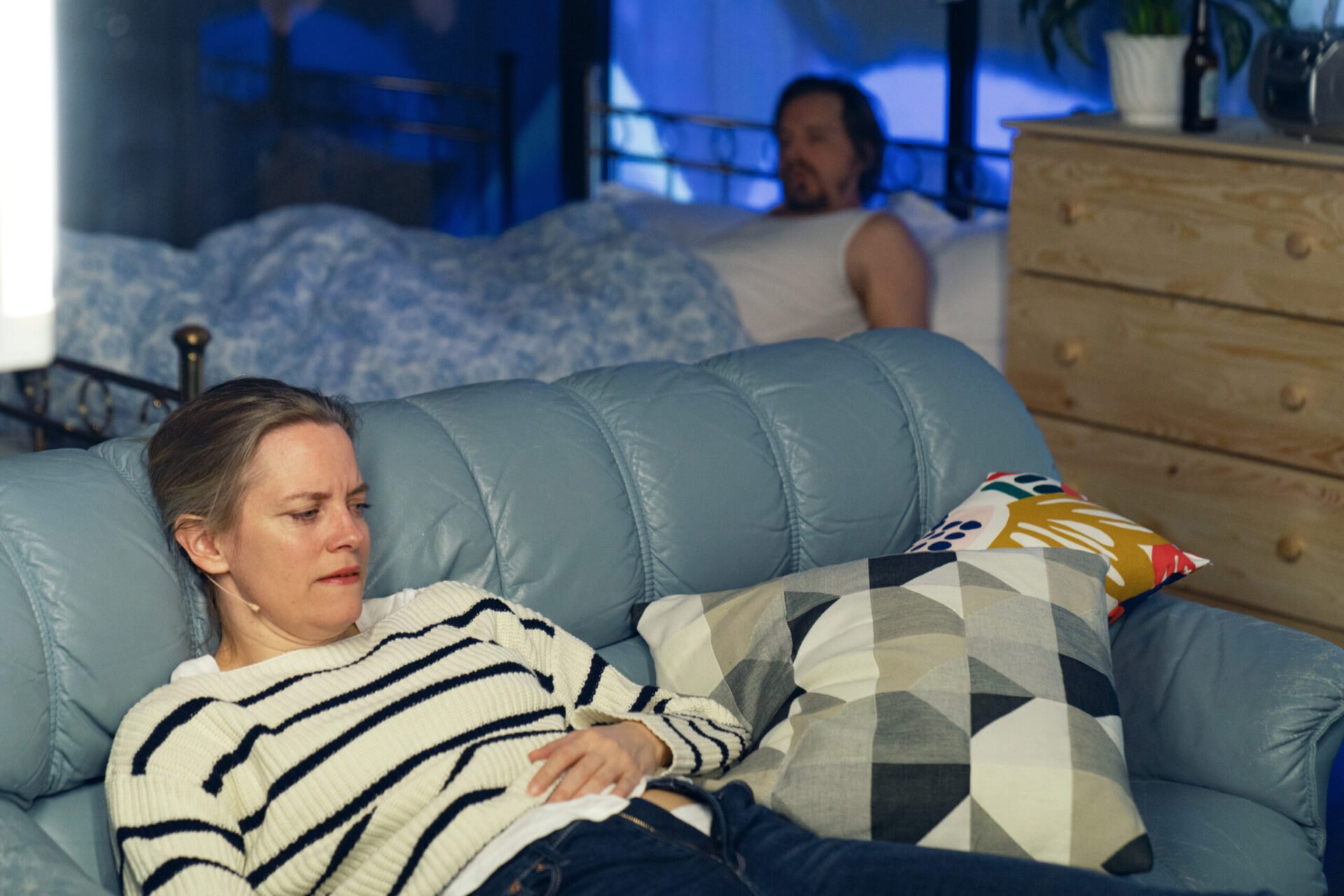 Kvinne ligger henslengt i en blå sofa