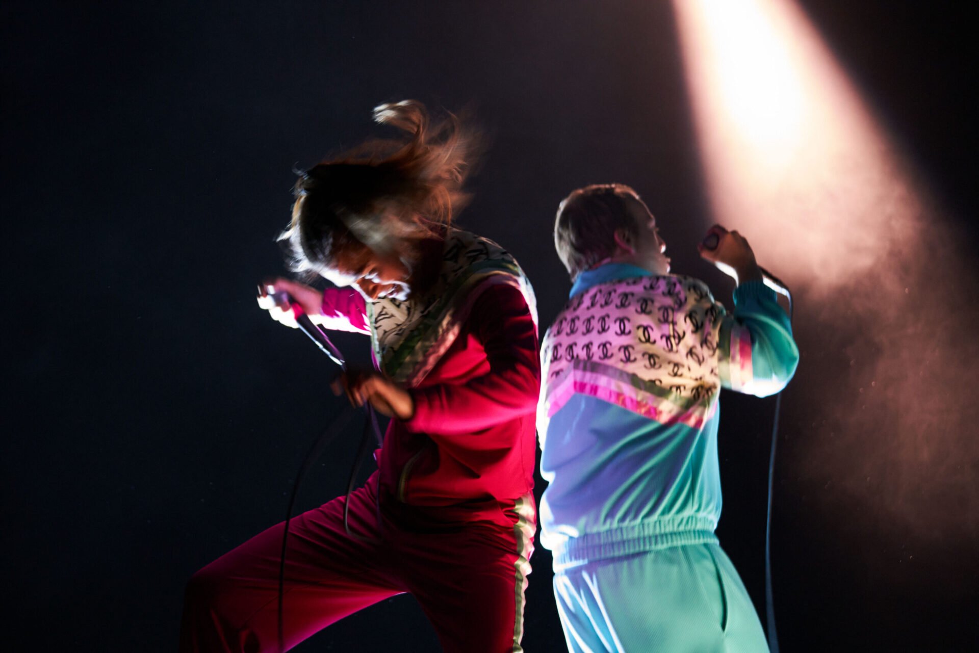 En mann og en kvinne i fargerike joggedrakter danser