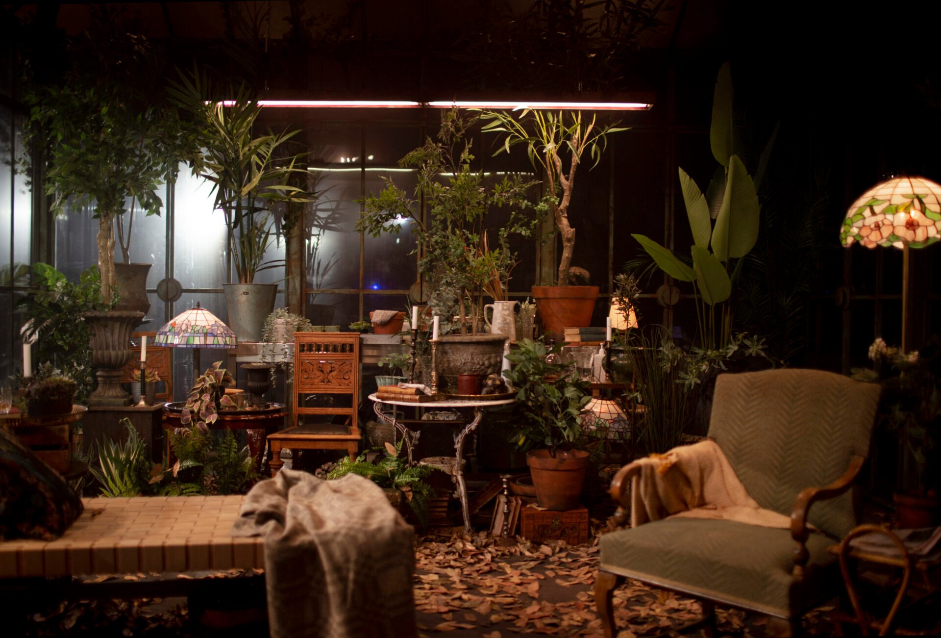 Interiøret i drivhuset med planter, lamper og stoler.