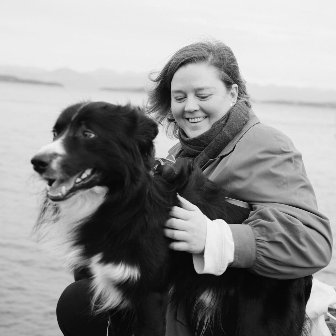 En smilende kvinne holder rundt en sort-og-hvit border collie.