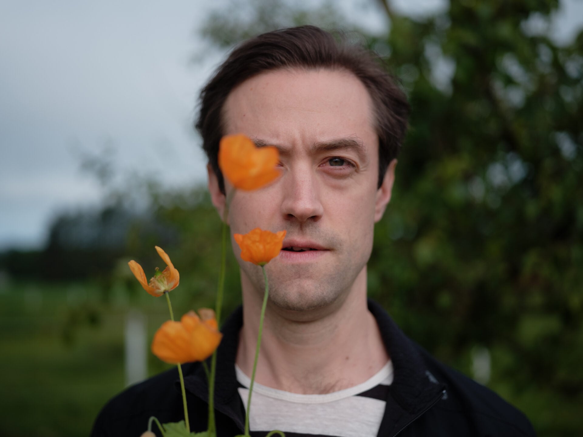 Matias Kuoppala med oransje blomster foran ansiktet