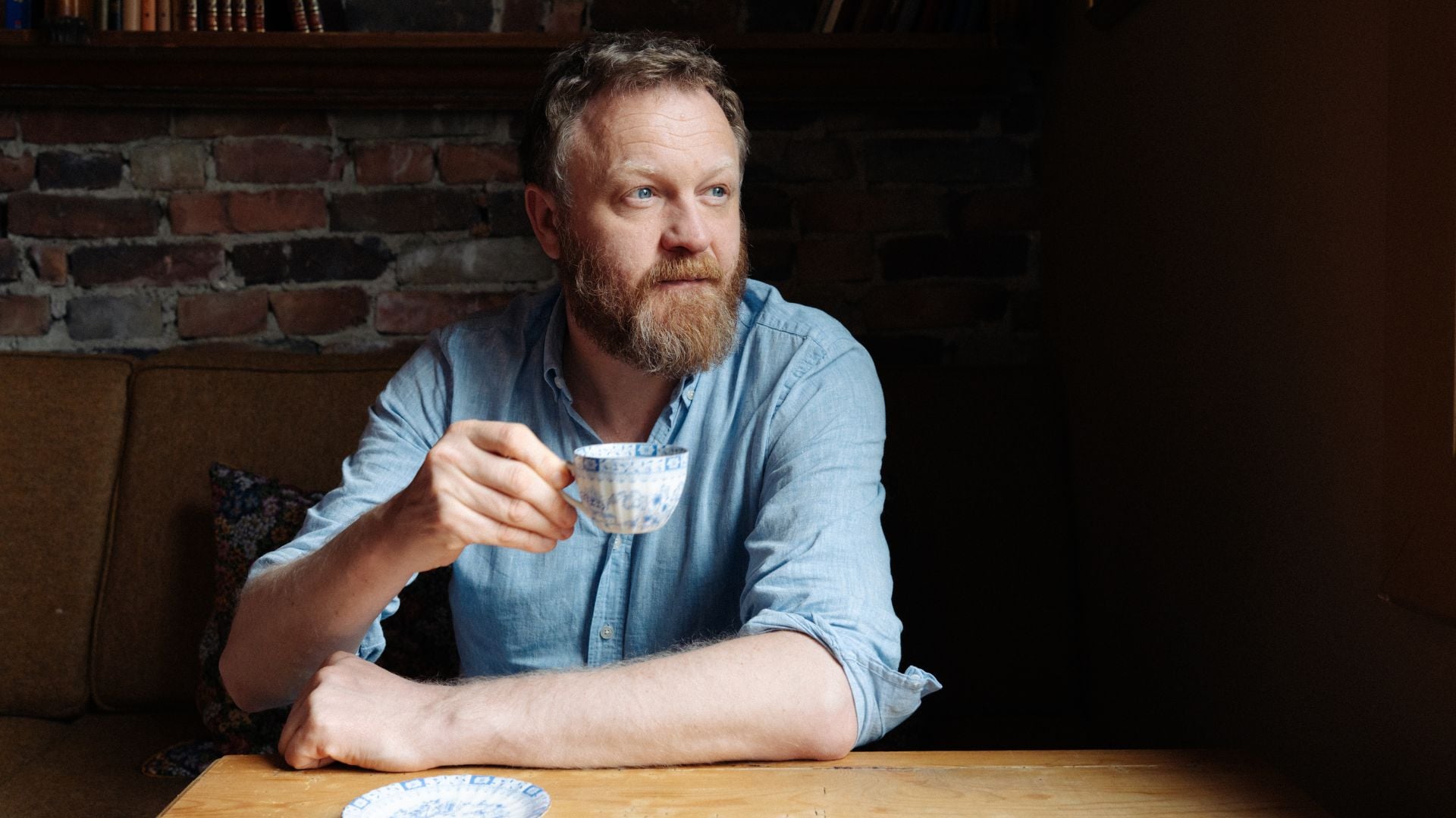 Glenn André Kaada sitter og drikker kaffe ved et trebord.